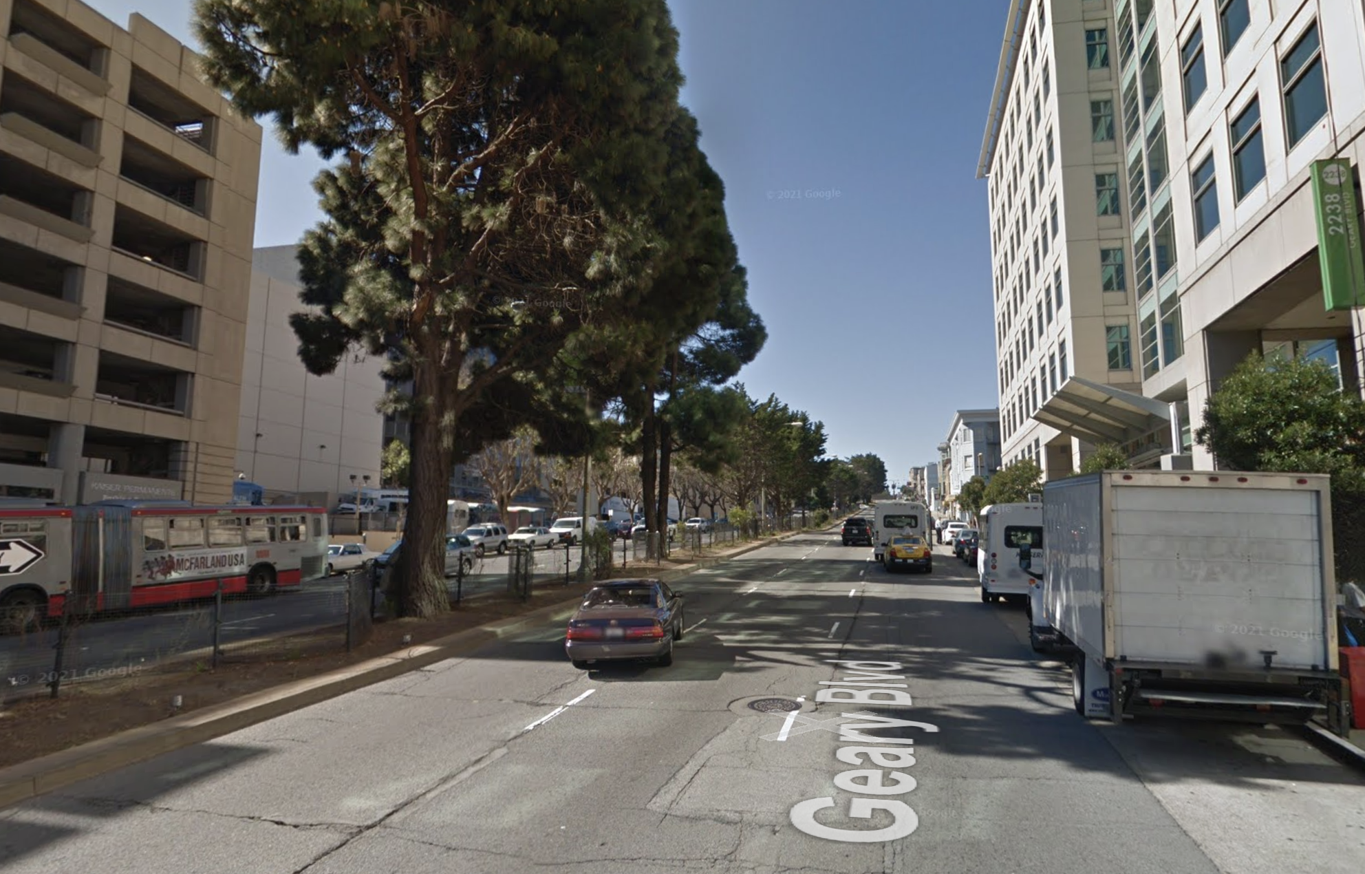 Geary Boulevard near Divisadero in 2015 before BRT. Three travel lanes each direction, planted center median with mature trees, curbside parking on both sides.